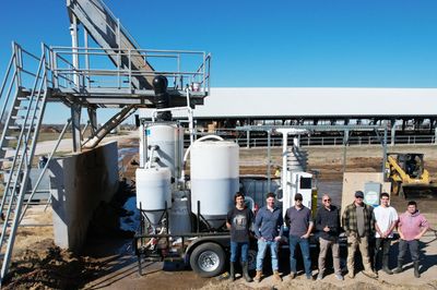 Greenhouse workers proudly standing front of machinery