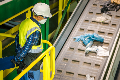 waste worker inspecting recyclable conveyor belt
